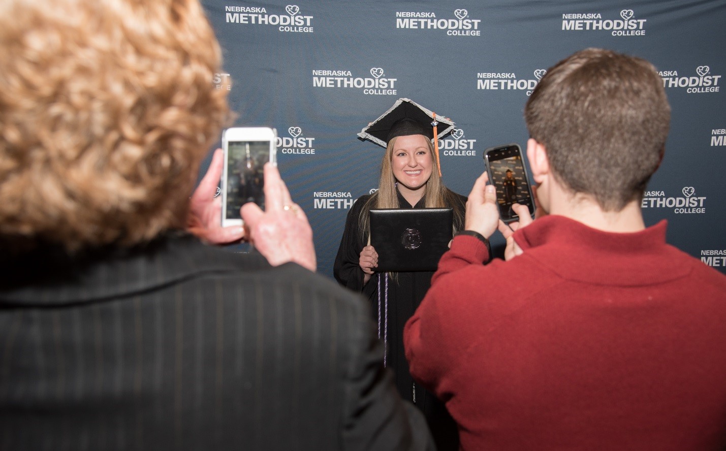 Proud family members take cell phone pics of their favorite graduate. 